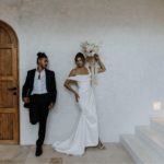 beautiful bride and groom taking artsy photo against plain wall next to some stairs