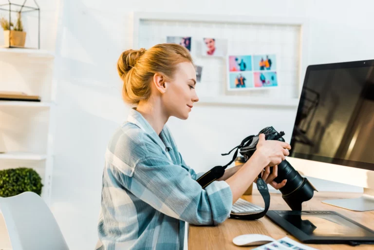 A photographer looking at a camera in her office.