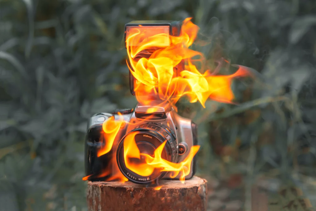 Close up of a DSLR camera on fire, sitting on a stump