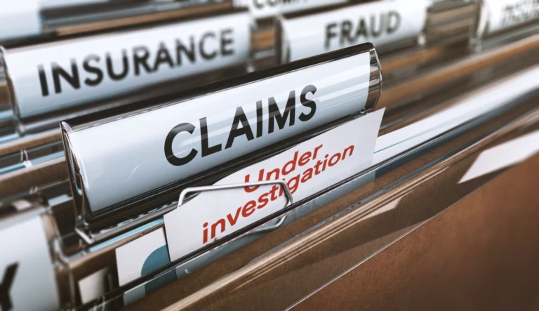 Close-up of file folders labeled Under Investigation, Claims, Insurance, and Fraud.