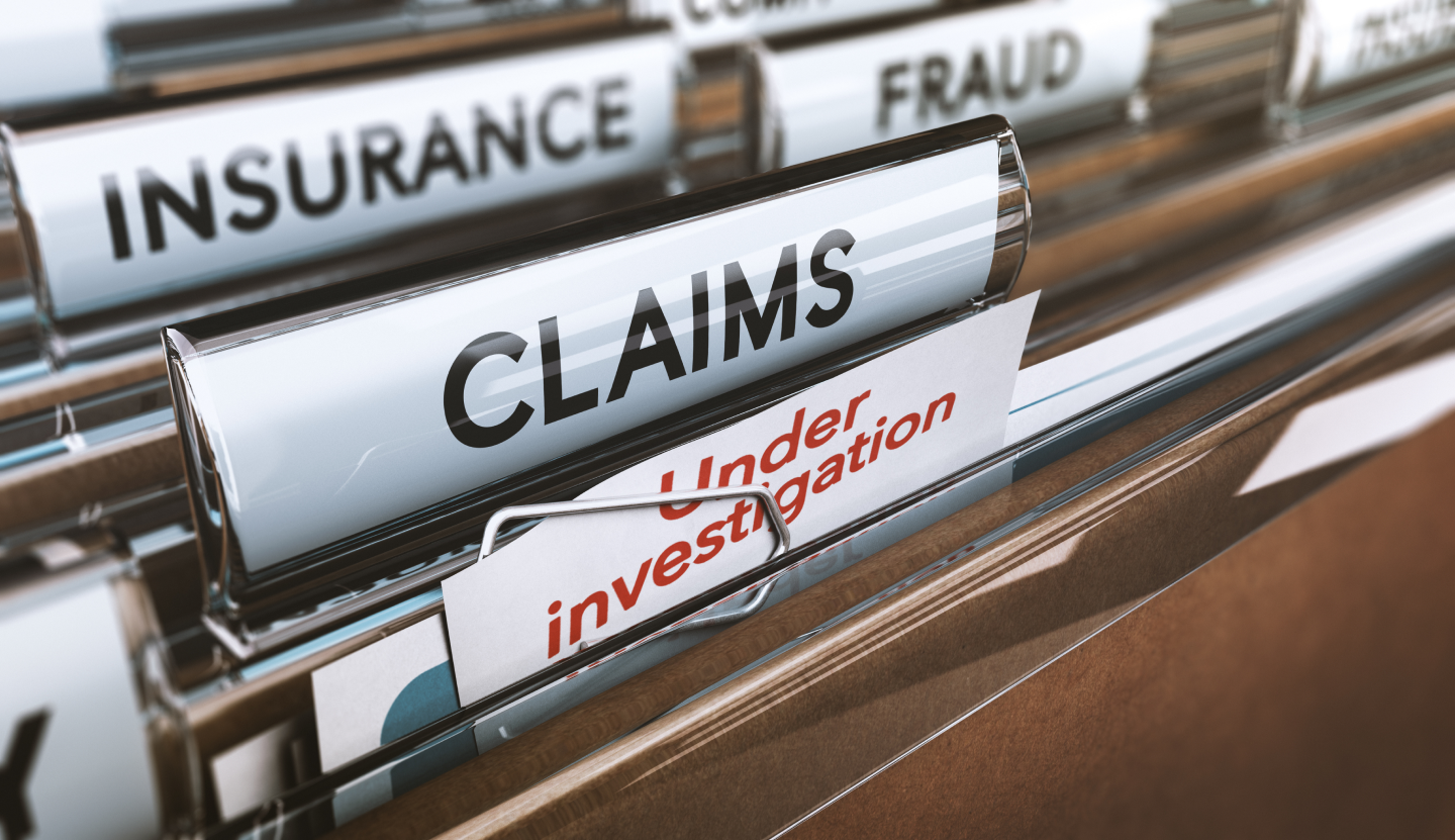 Close-up of file folders labeled Under Investigation, Claims, Insurance, and Fraud.