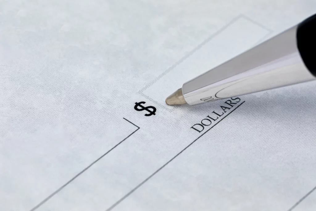 Close-up of a pen filling in the dollar amount on a check.