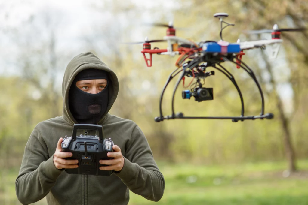 Man in black mask suspiciously controlling drone in a forest
