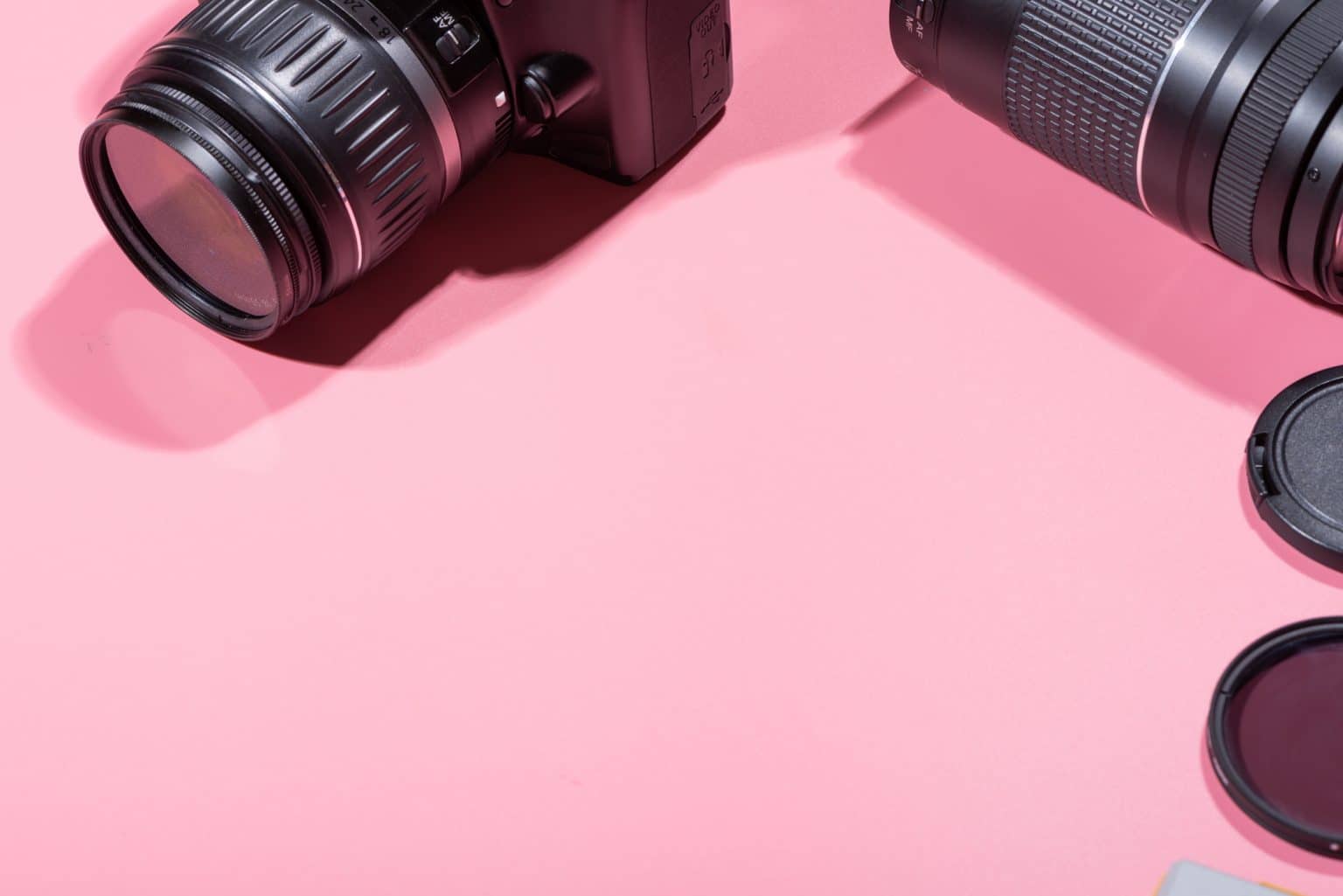 cameras and accessories on a pink background