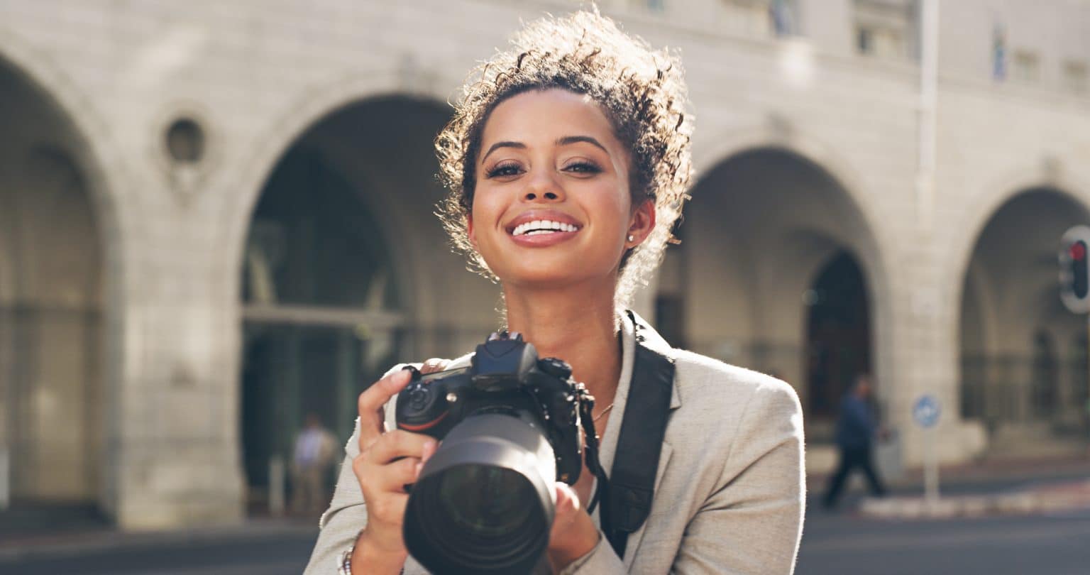 Cropped shot of an attractive young woman standing alone in the city and using her camera to take pictures