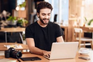 Freelancer bearded man typing at laptop sitting at desk.