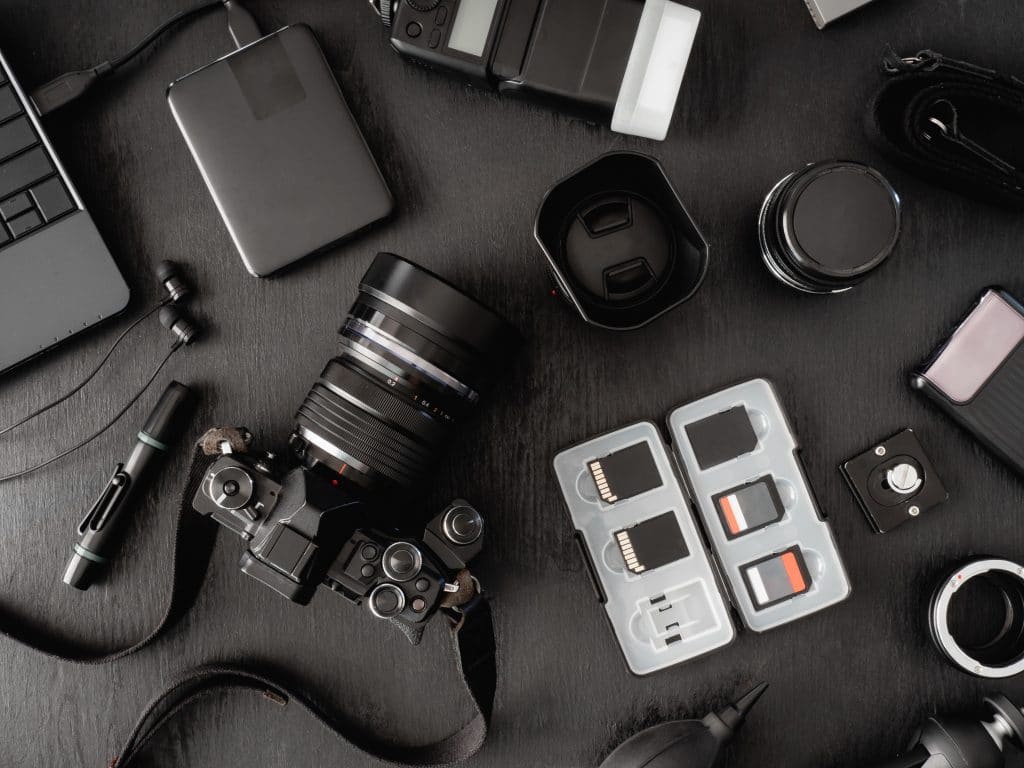 top view of work space photographer with digital camera, flash, cleaning kit, memory card, external harddisk, USB card reader, laptop and camera accessory on black table background